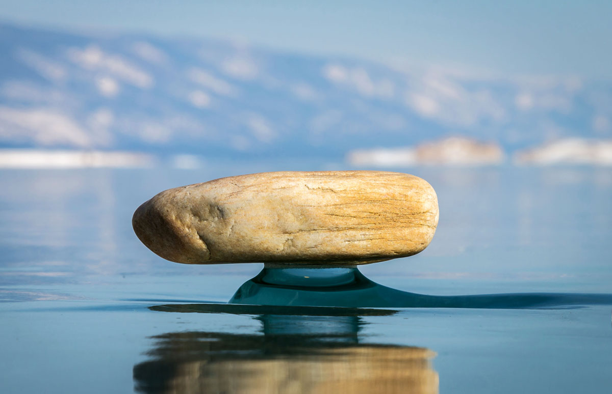  Une petite pierre se dresse sur une "jambe" au-dessus de la glace du lac Baïkal.